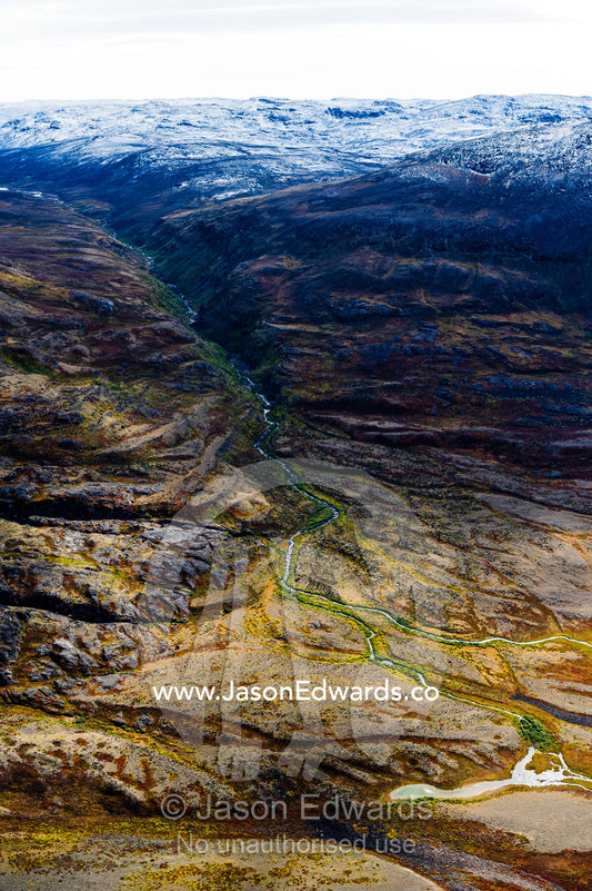 A winding river flows from a glacier and snakes it's way through a highland tundra valley. Tarajornitsut Highlands, Qeqqata Municipality, Kangerlussuaq, Greenland.