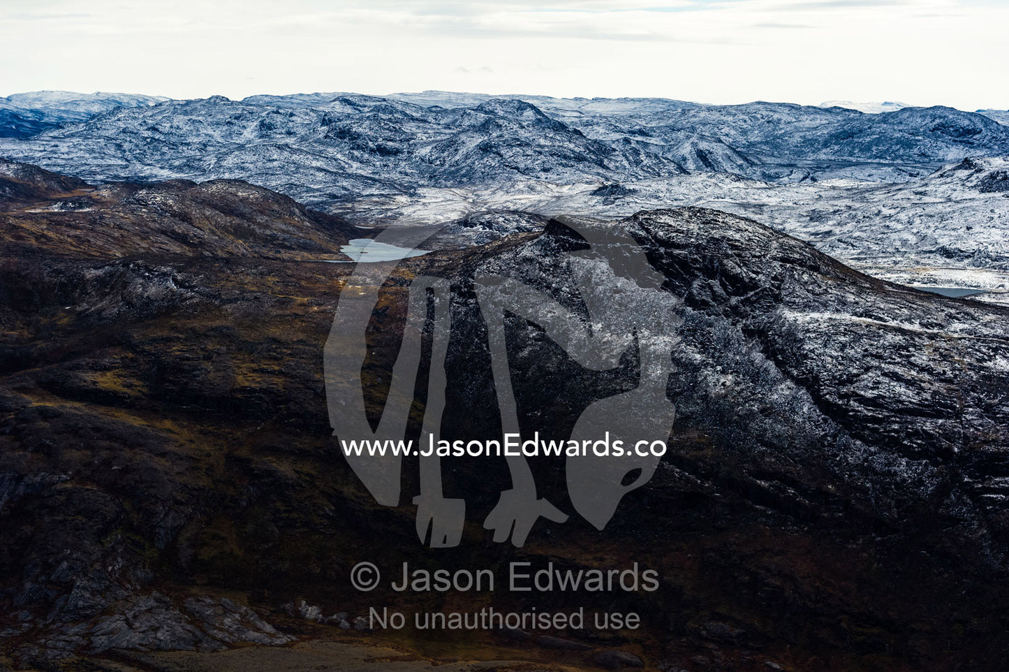 A dusting of snow covers barren and inhospitable mountain peaks on a highland tundra plateau. Tarajornitsut Highlands, Qeqqata Municipality, Kangerlussuaq, Greenland.