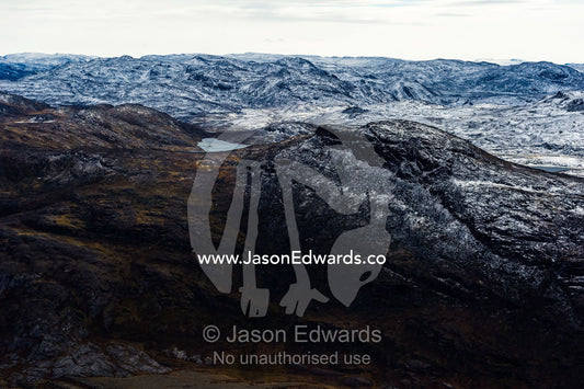 A dusting of snow covers barren and inhospitable mountain peaks on a highland tundra plateau. Tarajornitsut Highlands, Qeqqata Municipality, Kangerlussuaq, Greenland.