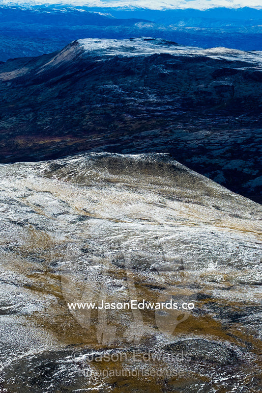 A dusting of snow covers mountain peaks on a highland tundra plateau. Tarajornitsut Highlands, Qeqqata Municipality, Kangerlussuaq, Greenland.