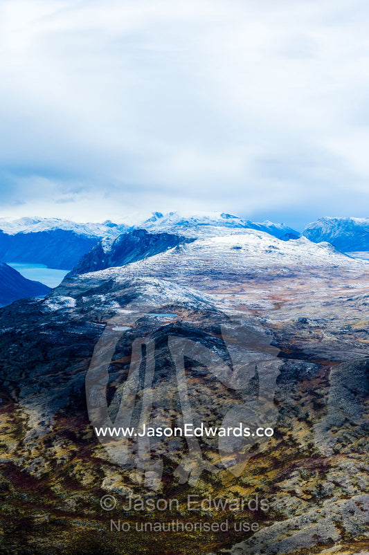 A dusting of snow covers mountain peaks on a highland tundra plateau. Tarajornitsut Highlands, Qeqqata Municipality, Kangerlussuaq, Greenland.