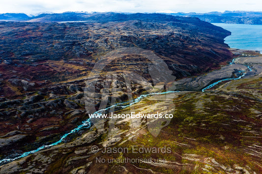 A winding river snakes it's way through a highland tundra valley to a fjord. Tarajornitsut Highlands, Qeqqata Municipality, Kangerlussuaq, Greenland.