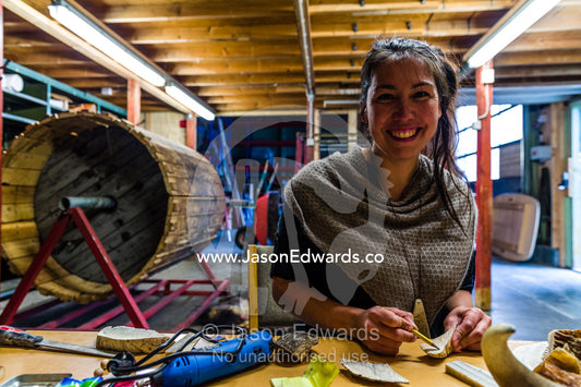 An artist carving jewellery from Musk Ox horns in her studio. Kangerlussuaq, Qeqqata Municipality, Greenland.