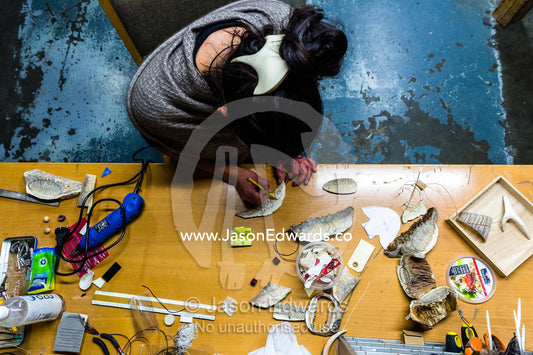 An artist carving jewelry from Musk Ox horns in her studio. Kangerlussuaq, Qeqqata Municipality, Greenland.