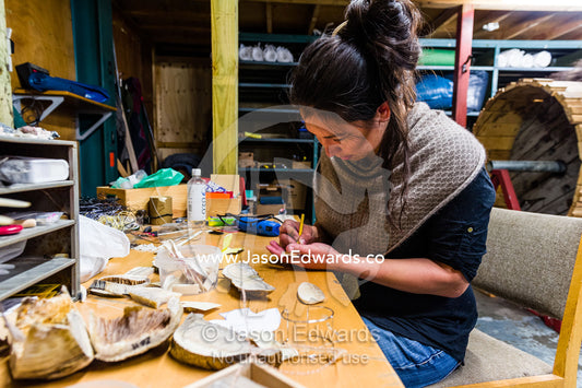 An artist carving jewelry from Musk Ox horns in her studio. Kangerlussuaq, Qeqqata Municipality, Greenland.