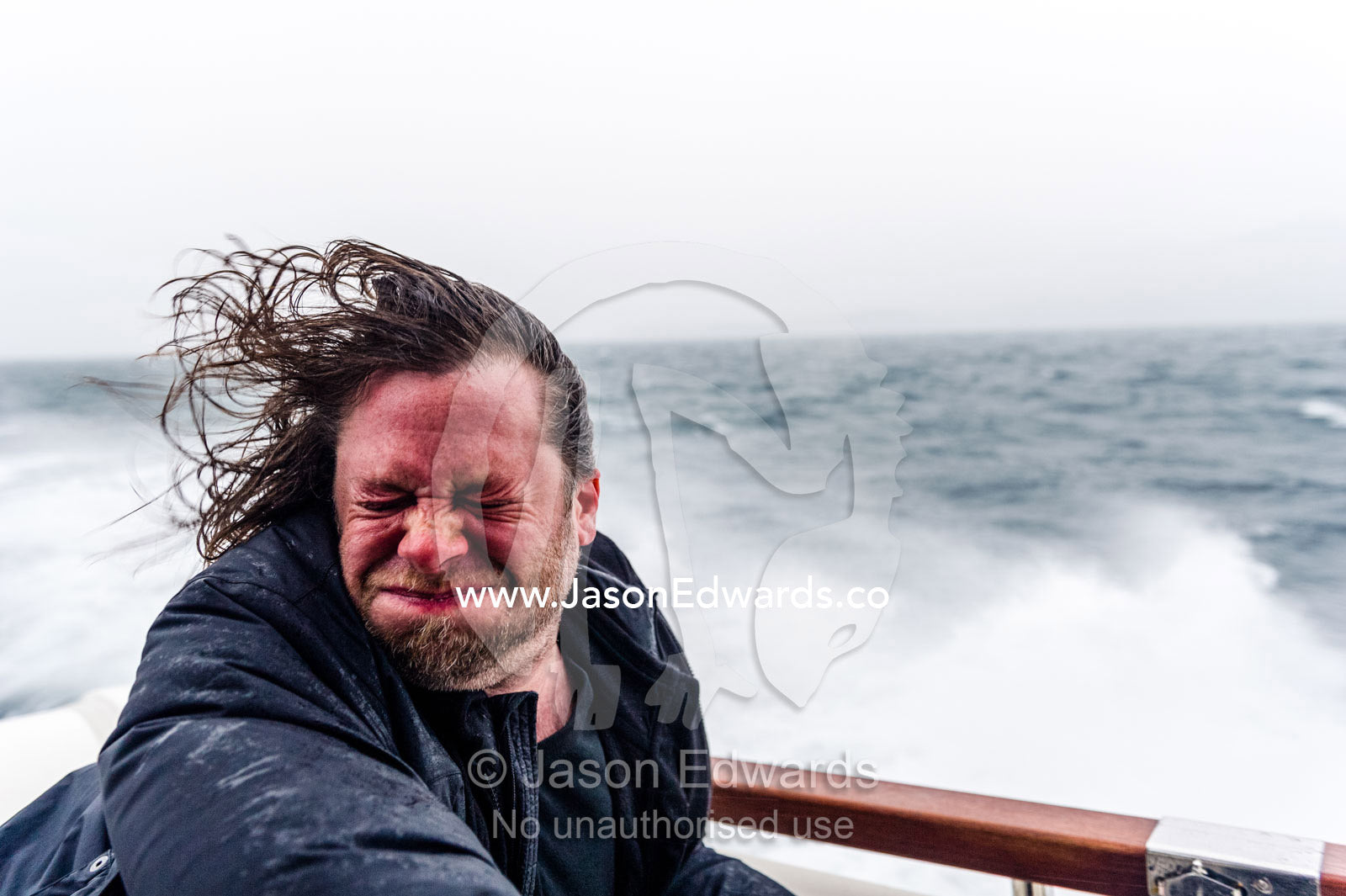 Spray and sleet lashes the face of a man on a speeding boat in a storm. Davis Strait, Maniitsoq, Sukkertoppen, Qeqqata Municipality, Greenland.