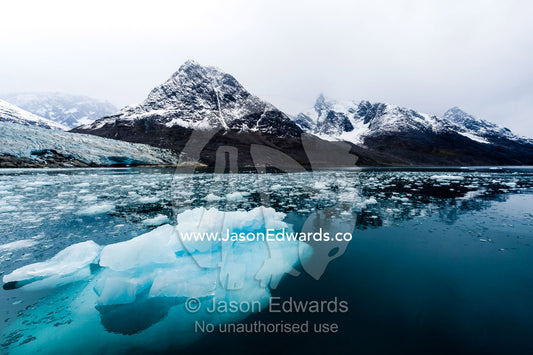 An iceberg carved from a glacier floating in the dark waters of an Arctic fjord. Fjord of Eternity, Maniitsoq, Sukkertoppen, Qeqqata Municipality, Greenland.