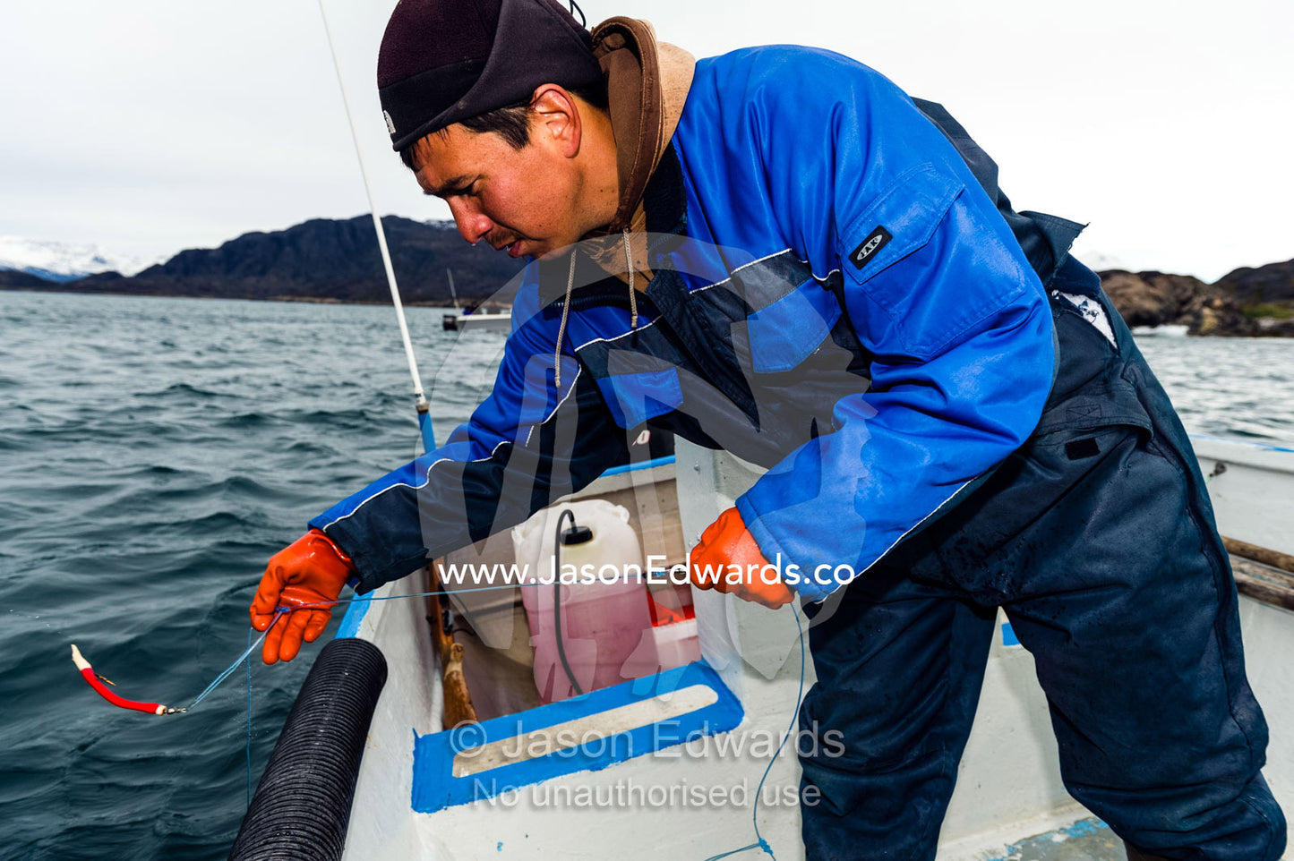An arctic fisherman fishing from a boat in a fiord. Davis Strait, Kangaamiut, Gammel Sukkertoppen, Qeqqata Municipality, Greenland.