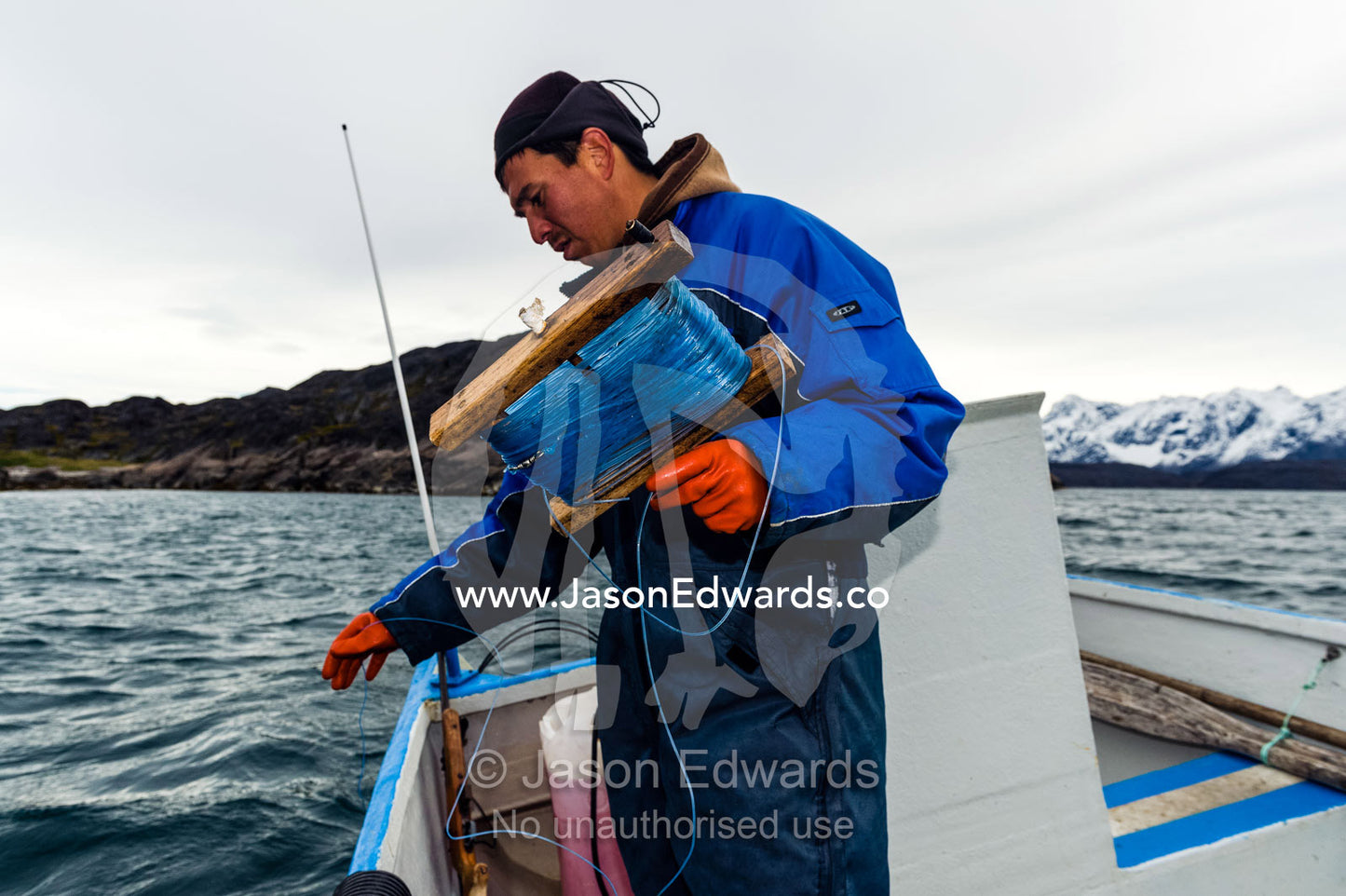 An arctic fisherman fishing from a boat in a fiord. Davis Strait, Kangaamiut, Gammel Sukkertoppen, Qeqqata Municipality, Greenland.
