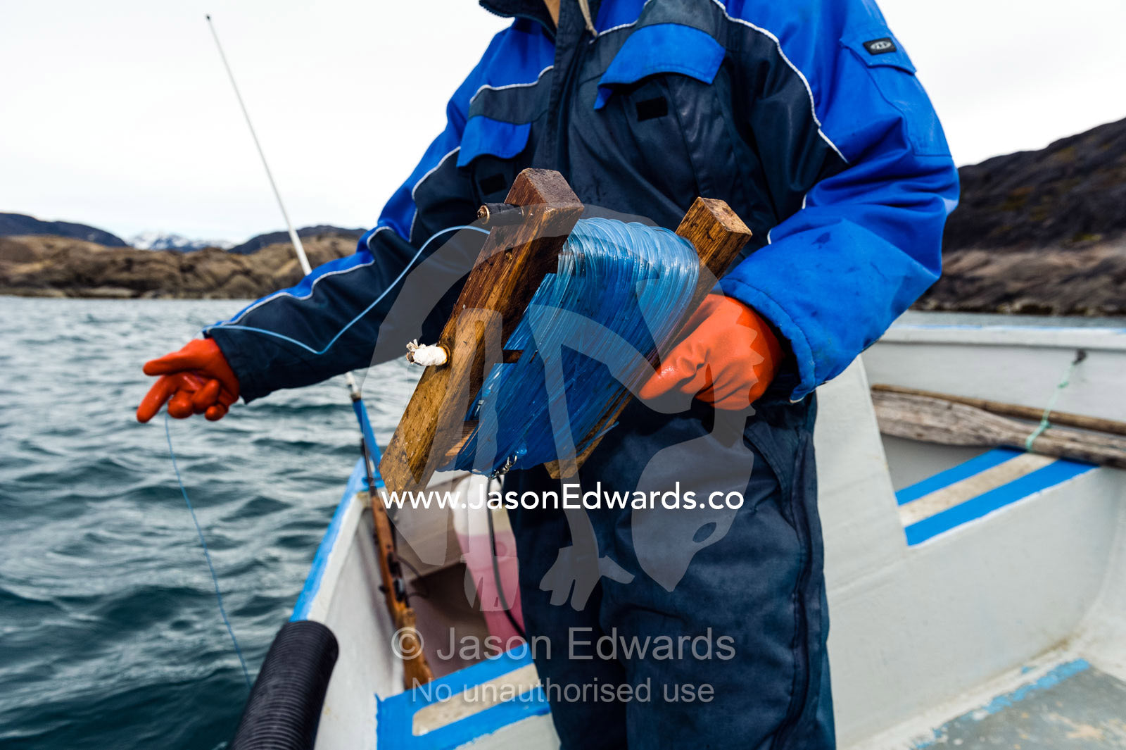 An arctic fisherman fishing from a boat in a fiord. Davis Strait, Kangaamiut, Gammel Sukkertoppen, Qeqqata Municipality, Greenland.