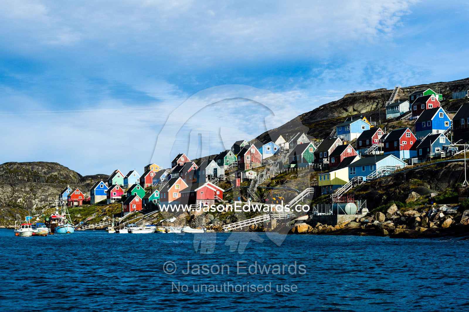 Colorful fishing houses perched on the rocky shoreline of an arctic island. Kangaamiut, Gammel Sukkertoppen, Qeqqata Municipality, Greenland.