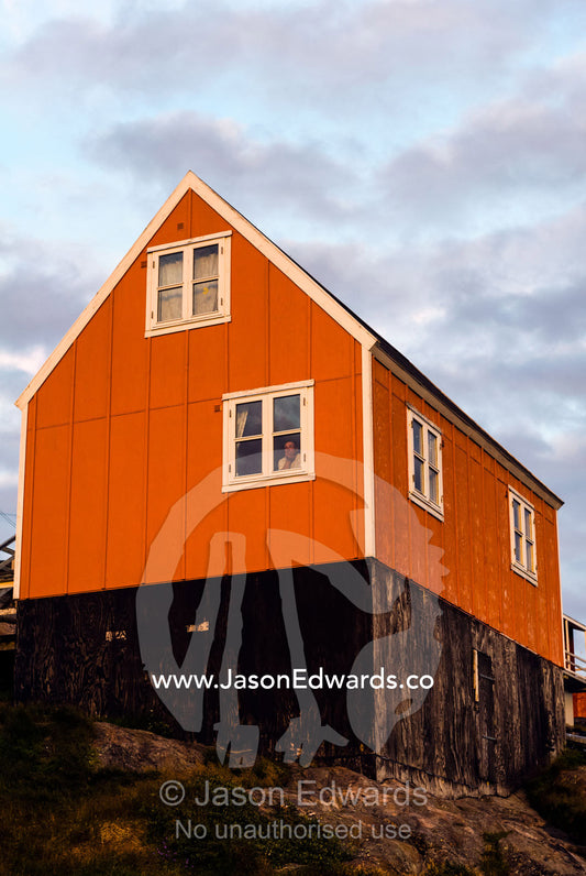 A bright orange cottage in a fishing village on an island. Kangaamiut, Gammel Sukkertoppen, Qeqqata Municipality, Greenland.