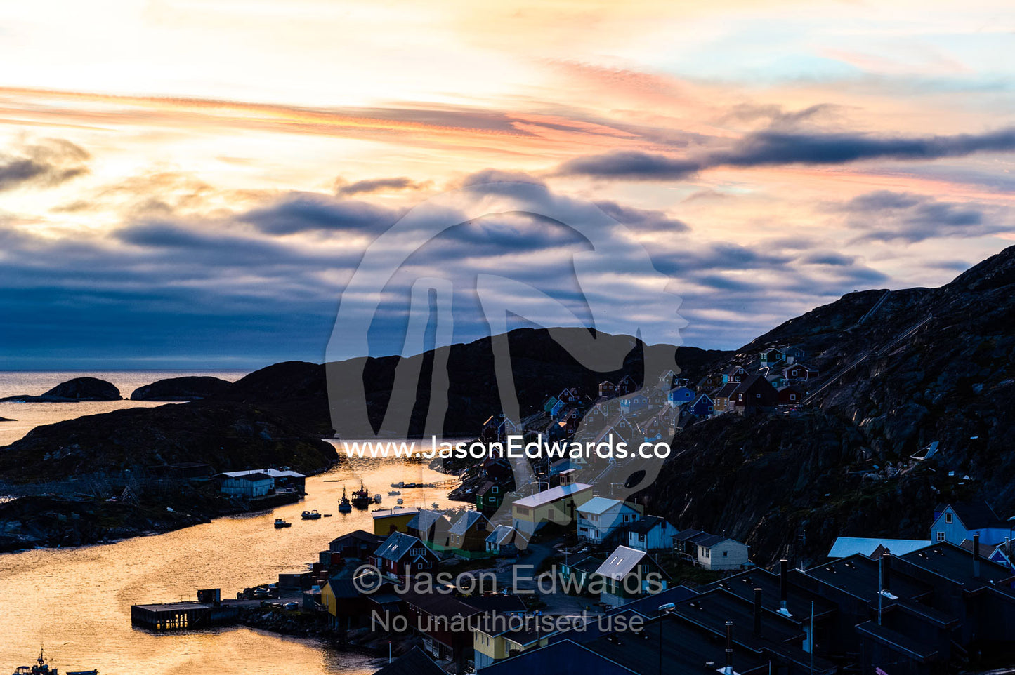 Sunset falls over an arctic fishing village on a rugged island. Davis Strait, Kangaamiut, Gammel Sukkertoppen, Qeqqata Municipality, Greenland.