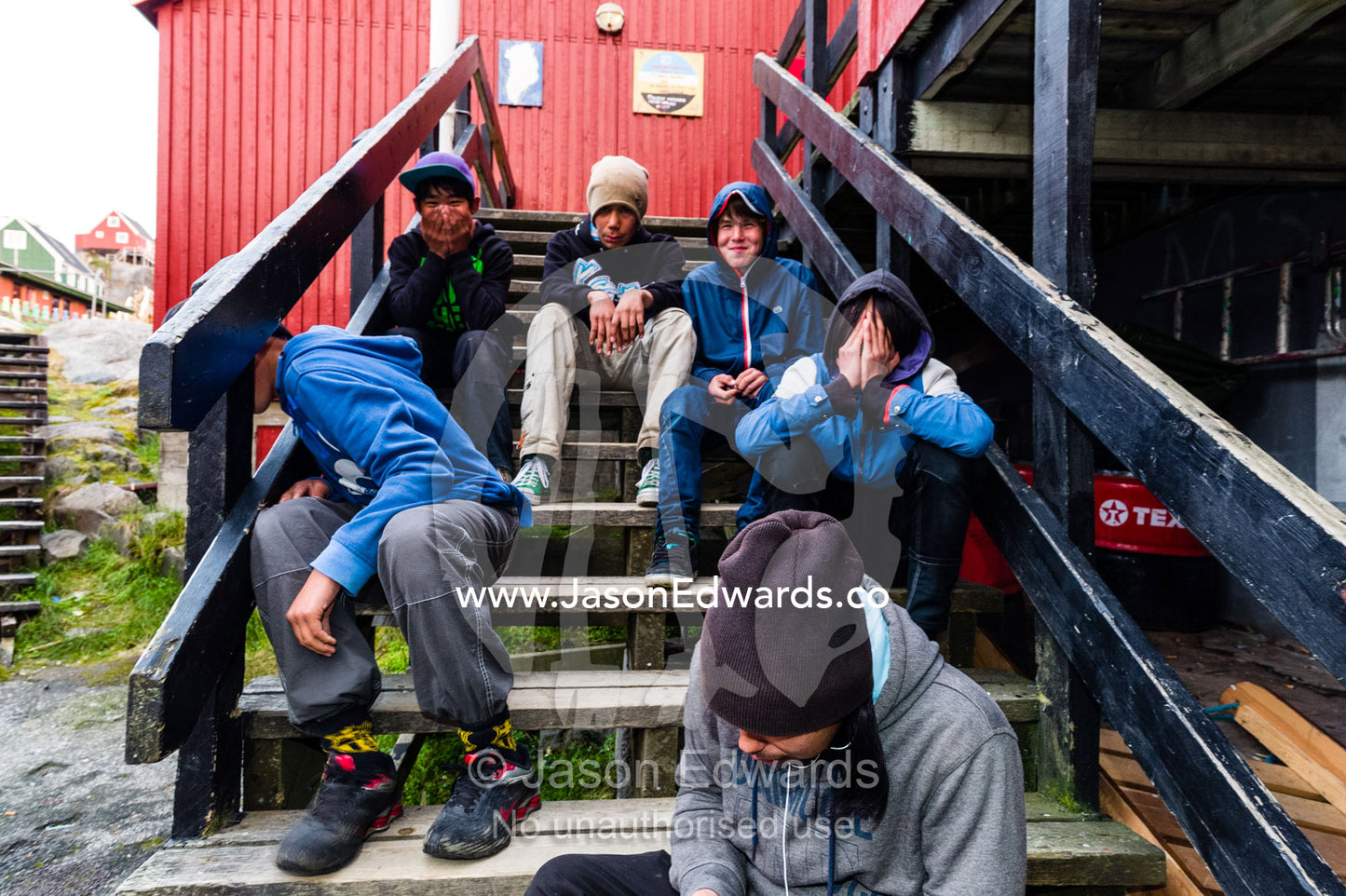 Teenage boys laughing and playing on the steps of a high school in an arctic village. Kangaamiut, Gammel Sukkertoppen, Qeqqata Municipality, Greenland.