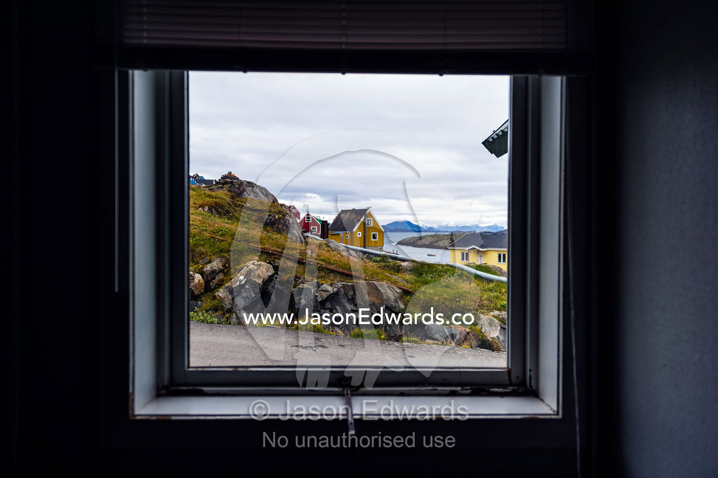 The view of cottages in an arctic village through a weather-sealed window. Kangaamiut, Gammel Sukkertoppen, Qeqqata Municipality, Greenland.
