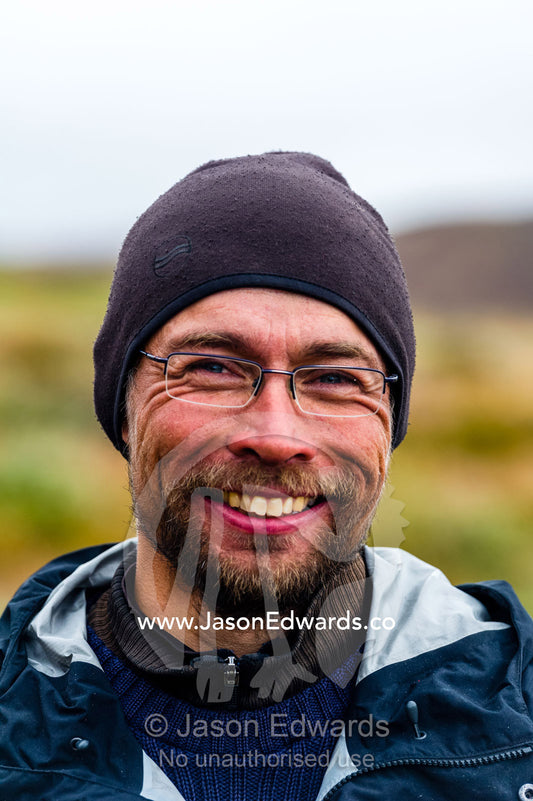The smiling face of a Greenland guide hiking on the tundra. Ammalortup Nunaa Highland, Kangerlussuaq, Qeqqata Municipality, Greenland.