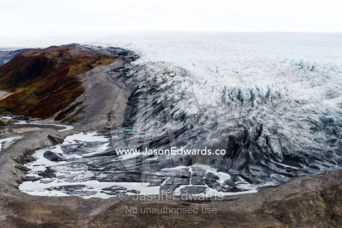 A river skirts a pile of rock, sediment and silt debris deposited by the leading edge of a glacier. Qinnguata Kuussua River, Russell Glacier, Greenland Ice Sheet, Qeqqata Municipality, Kangerlussuaq, Greenland.