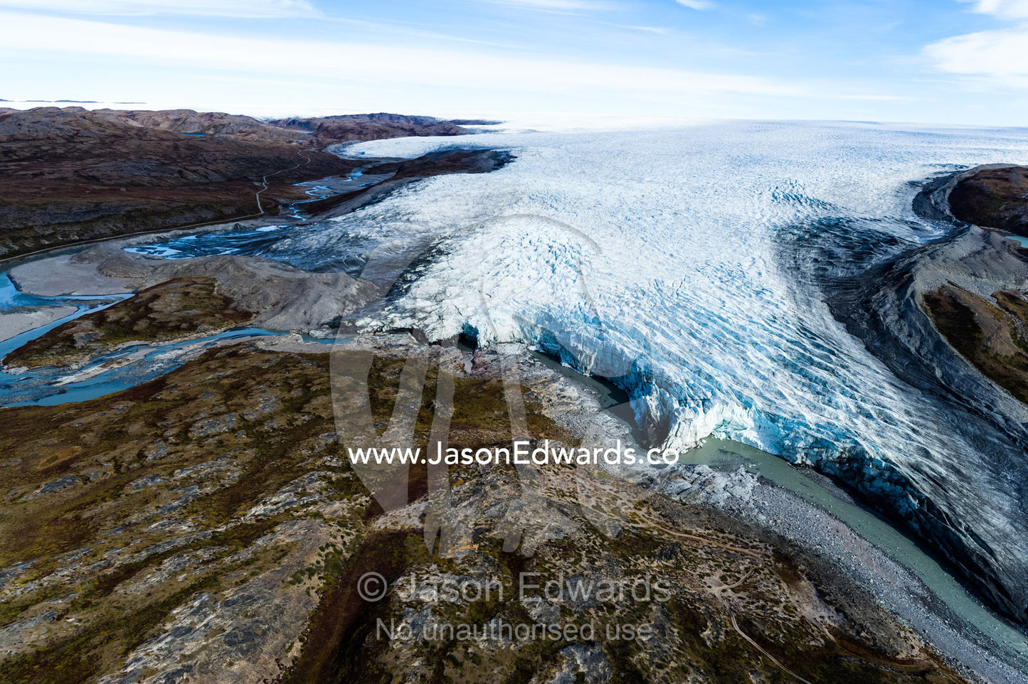 A river of meltwater flows from an enormous glacier into a floodplain. Qinnguata Kuussua River, Russell Glacier, Greenland Ice Sheet, Qeqqata Municipality, Kangerlussuaq, Greenland.