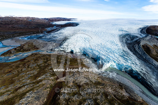 A river of meltwater flows from an enormous glacier into a floodplain. Qinnguata Kuussua River, Russell Glacier, Greenland Ice Sheet, Qeqqata Municipality, Kangerlussuaq, Greenland.