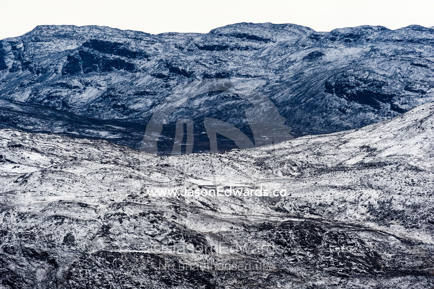A dusting of snow covers barren and inhospitable mountain peaks on a highland tundra plateau. Tarajornitsut Highlands, Qeqqata Municipality, Kangerlussuaq, Greenland.