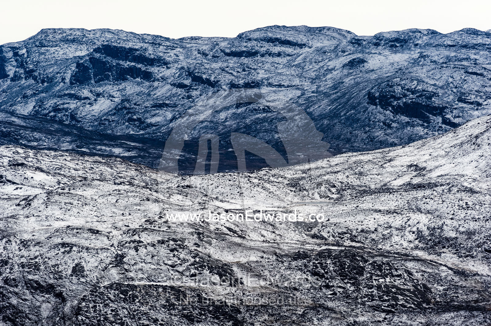A dusting of snow covers barren and inhospitable mountain peaks on a highland tundra plateau. Tarajornitsut Highlands, Qeqqata Municipality, Kangerlussuaq, Greenland.