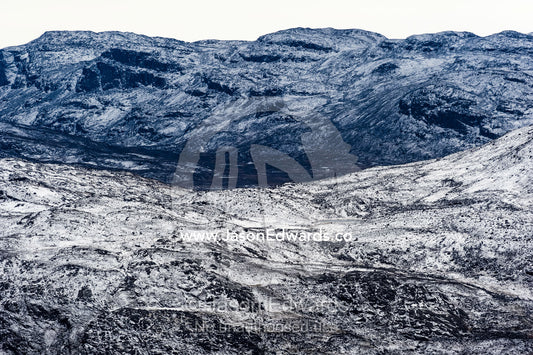 A dusting of snow covers barren and inhospitable mountain peaks on a highland tundra plateau. Tarajornitsut Highlands, Qeqqata Municipality, Kangerlussuaq, Greenland.