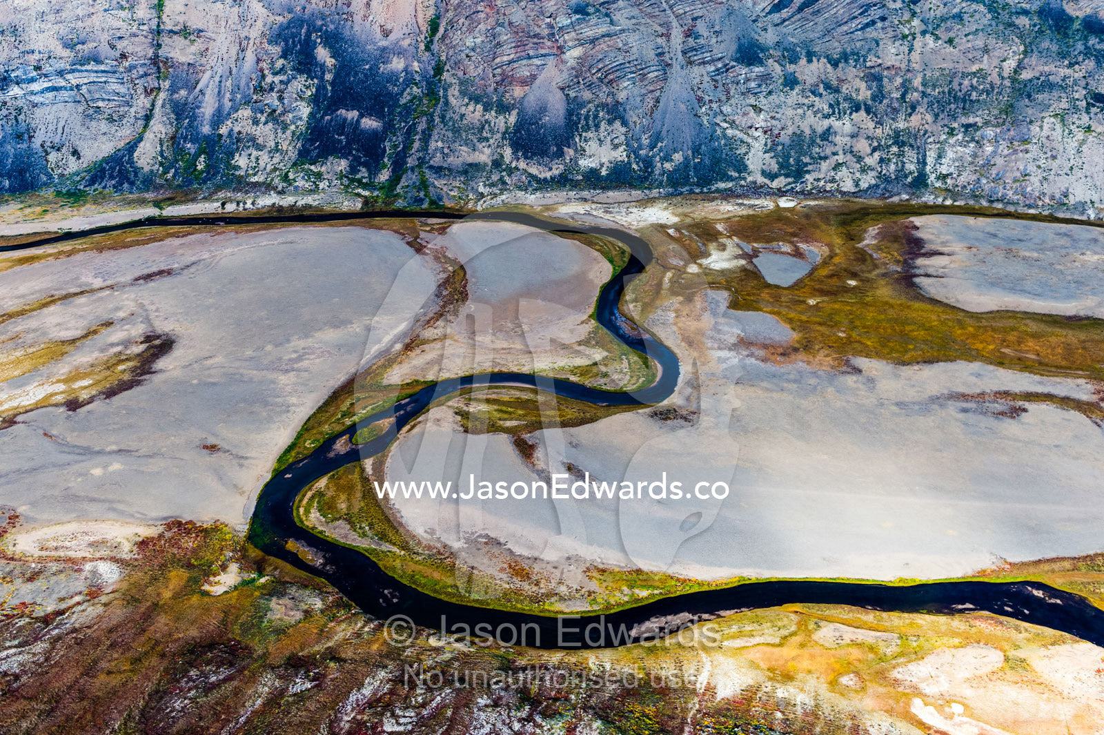 A winding river snakes its way across a highland tundra valley floor. Tarajornitsut Highlands, Qeqqata Municipality, Kangerlussuaq, Greenland.