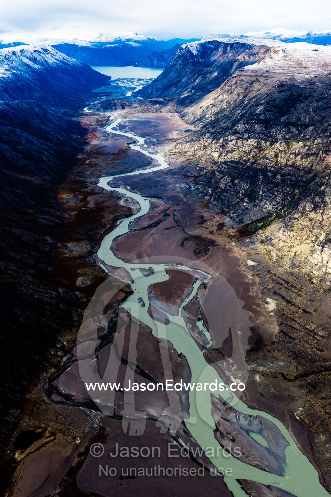 A winding river snakes its way through a highland tundra valley to a fiord. Tarajornitsut Highlands, Qeqqata Municipality, Kangerlussuaq, Greenland.