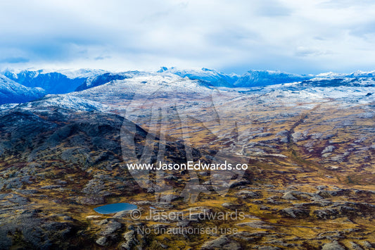 A dusting of snow covers mountain peaks on a highland tundra plateau. Tarajornitsut Highlands, Qeqqata Municipality, Kangerlussuaq, Greenland.