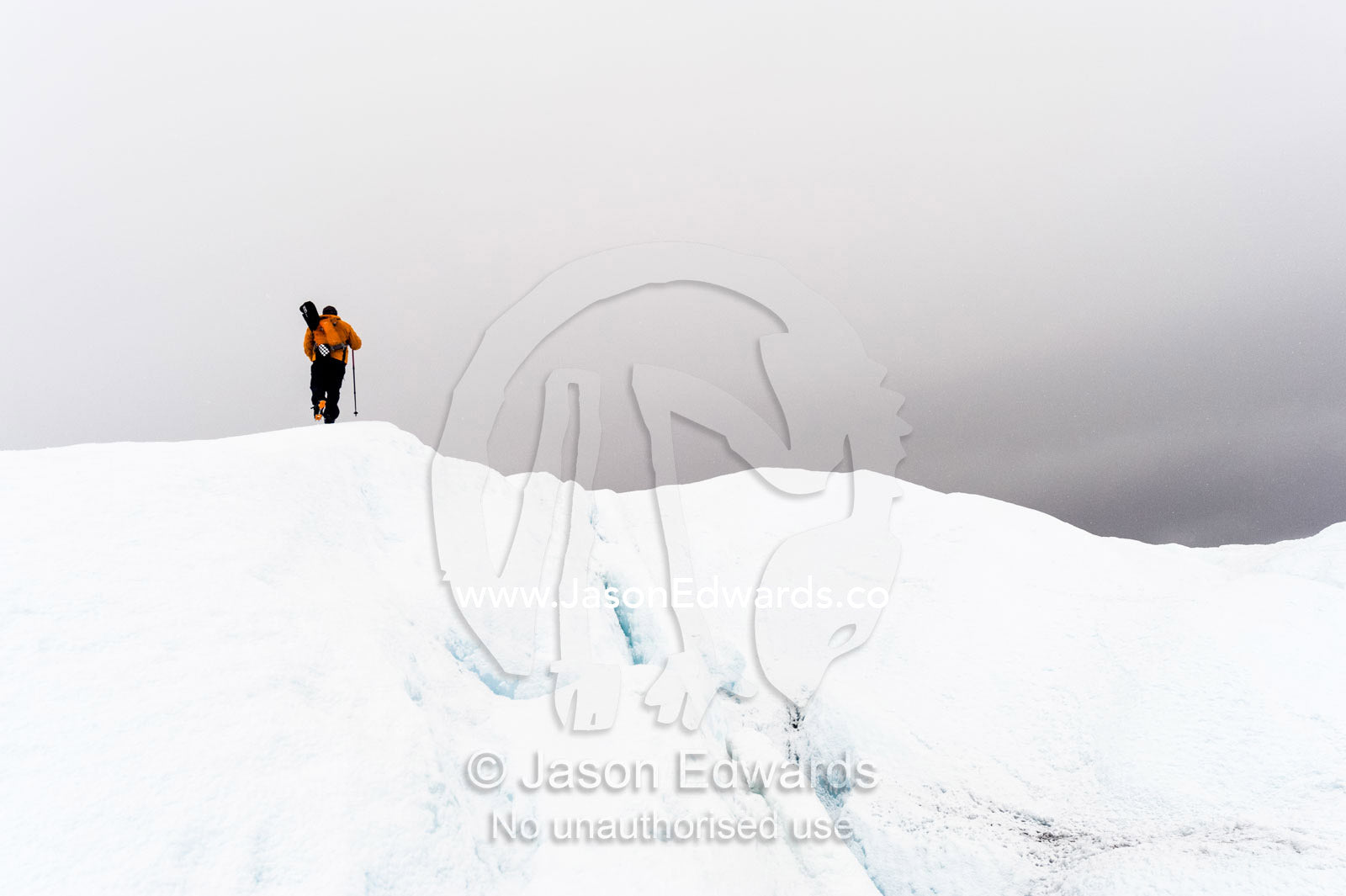 A solitary hiker on the frozen and barren wasteland of folded ice and crevasse on the Greenland Ice Sheet. Greenland Ice Sheet, Qeqqata Municipality, Kangerlussuaq, Greenland.
