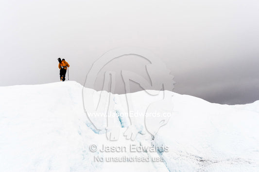 A solitary hiker on the frozen and barren wasteland of folded ice and crevasse on the Greenland Ice Sheet. Greenland Ice Sheet, Qeqqata Municipality, Kangerlussuaq, Greenland.
