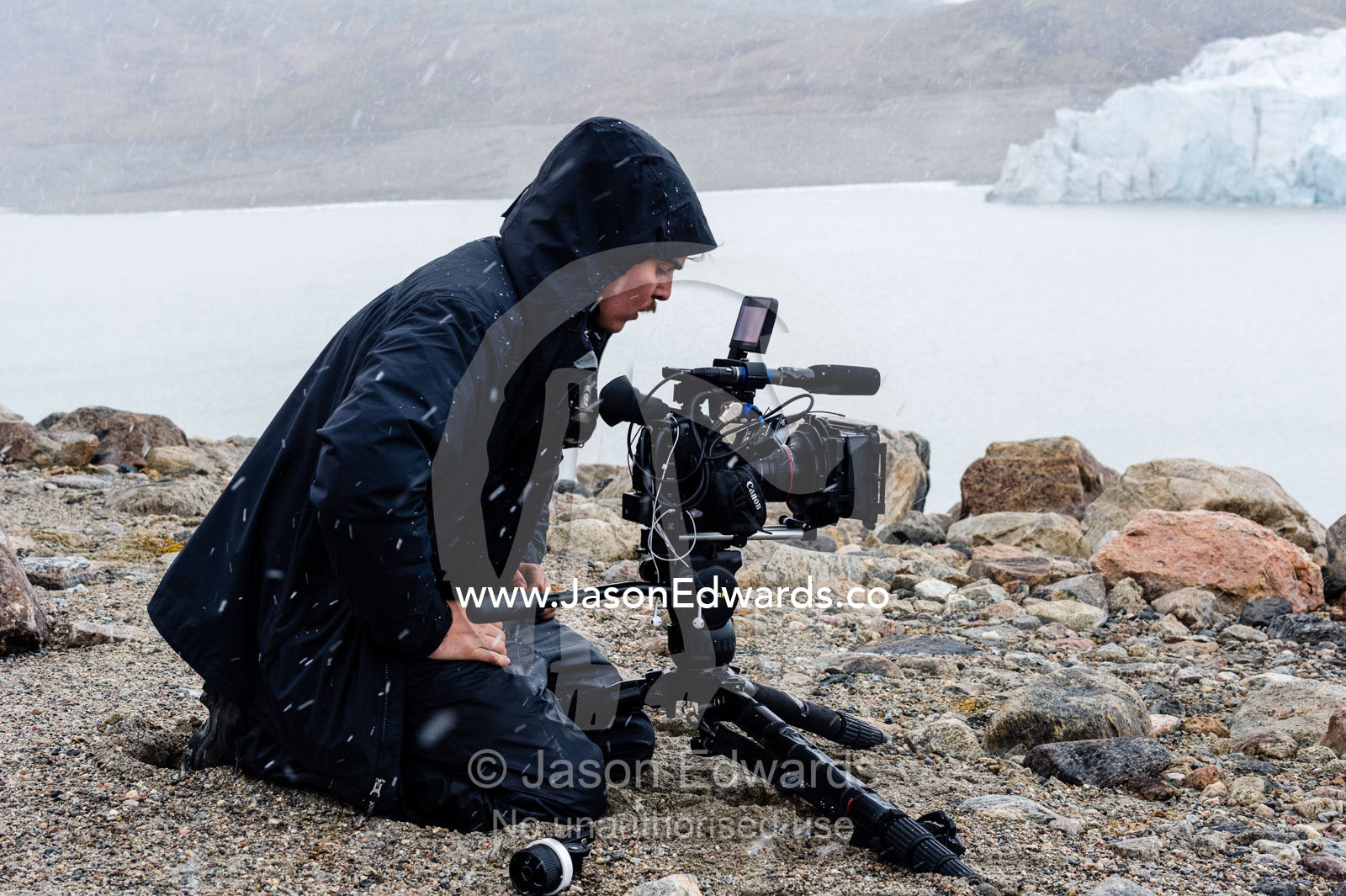 A cameraman filming a glacier during a snow storm. Isunngua Highland, Greenland Ice Sheet, Kangerlussuaq, Qeqqata Municipality, Greenland.