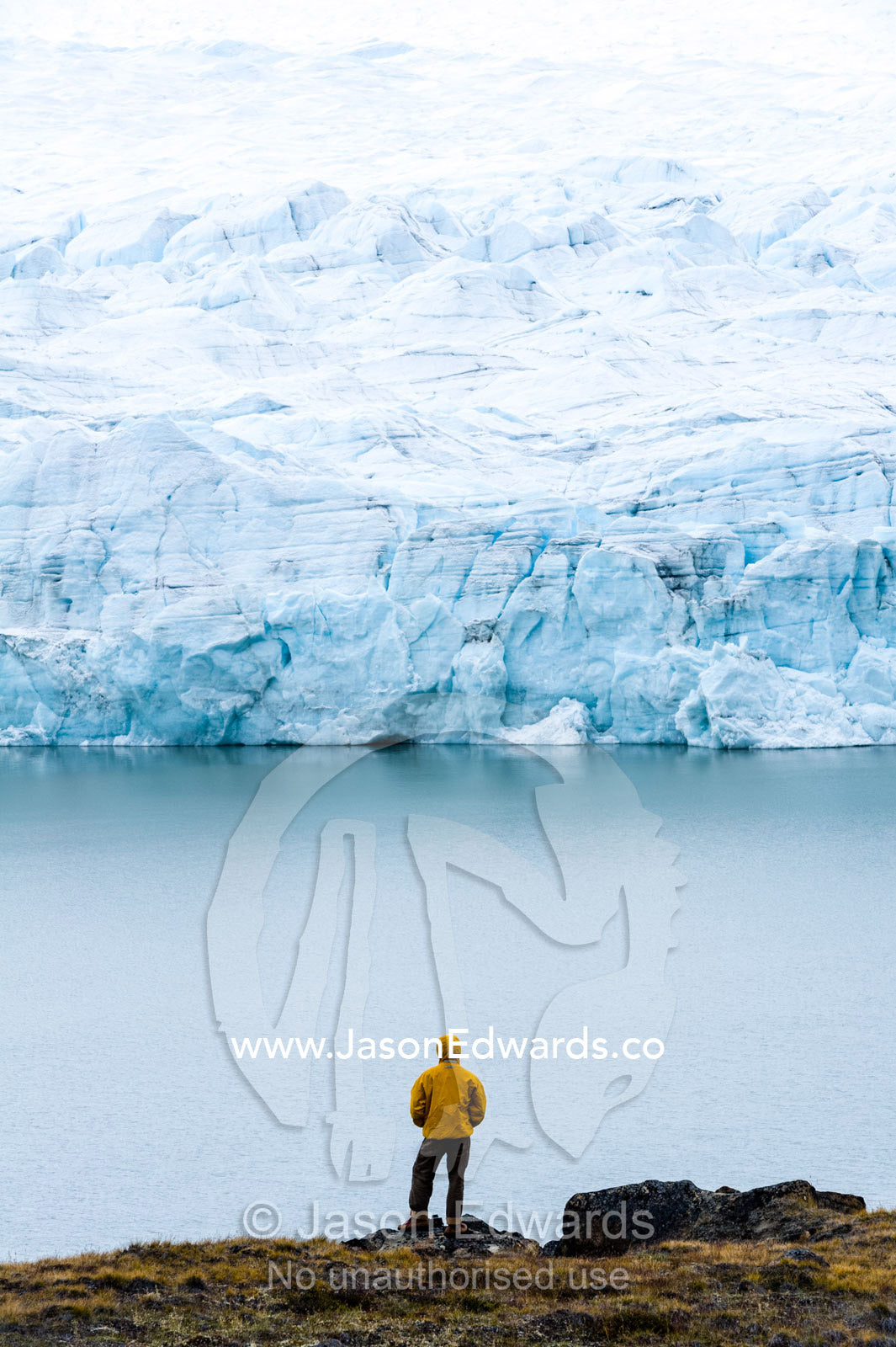 A hiker dwarfed by the fracture zone of a glacier on the Greenland Ice Sheet. Isunngua Highland, Greenland Ice Sheet, Kangerlussuaq, Qeqqata Municipality, Greenland.
