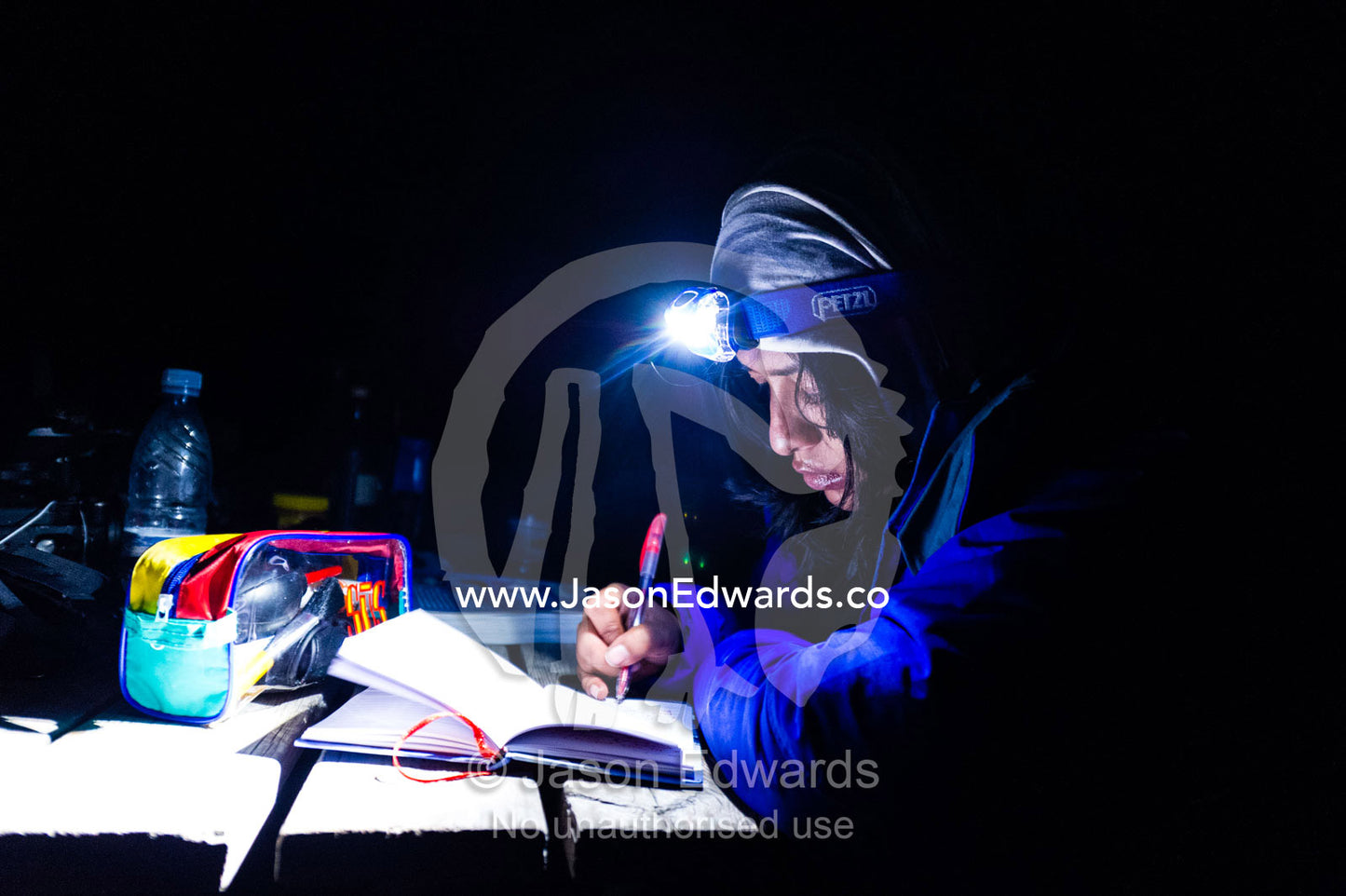 A photographer writing field notes in her journal at night. Russell Glacier, Greenland Ice Sheet, Qeqqata Municipality, Kangerlussuaq, Greenland.