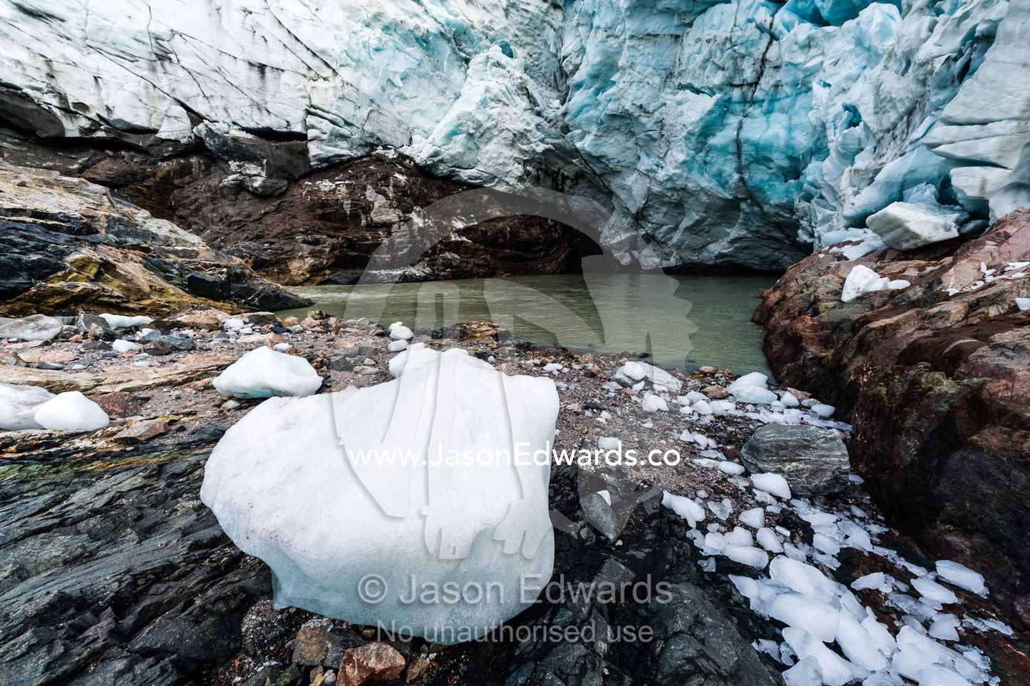 A block of ice carved from a glacier resting on the rocky ground beneath a glacier fracture zone. Russell Glacier, Greenland Ice Sheet, Qeqqata Municipality, Kangerlussuaq, Greenland.