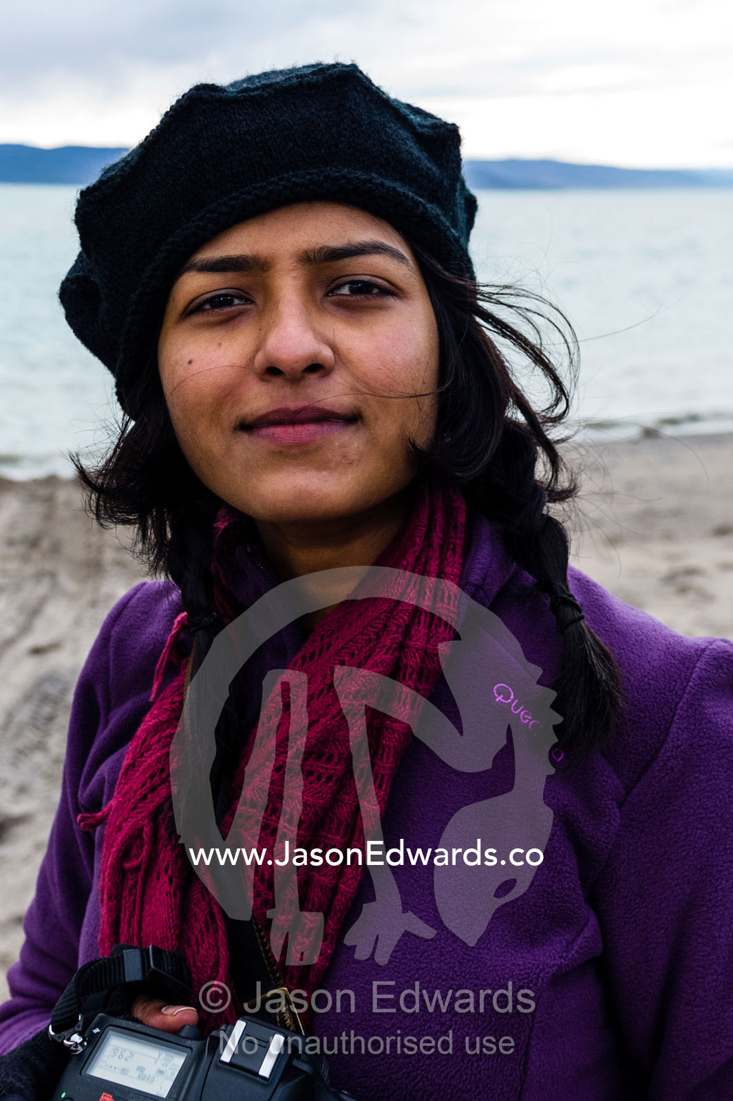 An Indian woman standing on the shore of a fjord in the arctic. Kangerlussuaq Port, Kangerlussuaq Fjord, Kangerlussuaq, Qeqqata Municipality, Greenland.