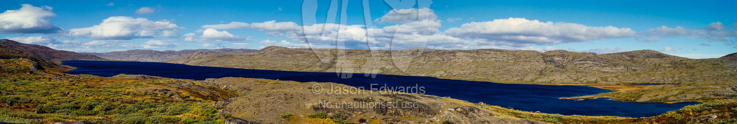 An alpine lake surrounded by barren mountains and lush tundra. Tasersuatsiaq Lake, Kangerlussuaq, Qeqqata Municipality, Greenland.