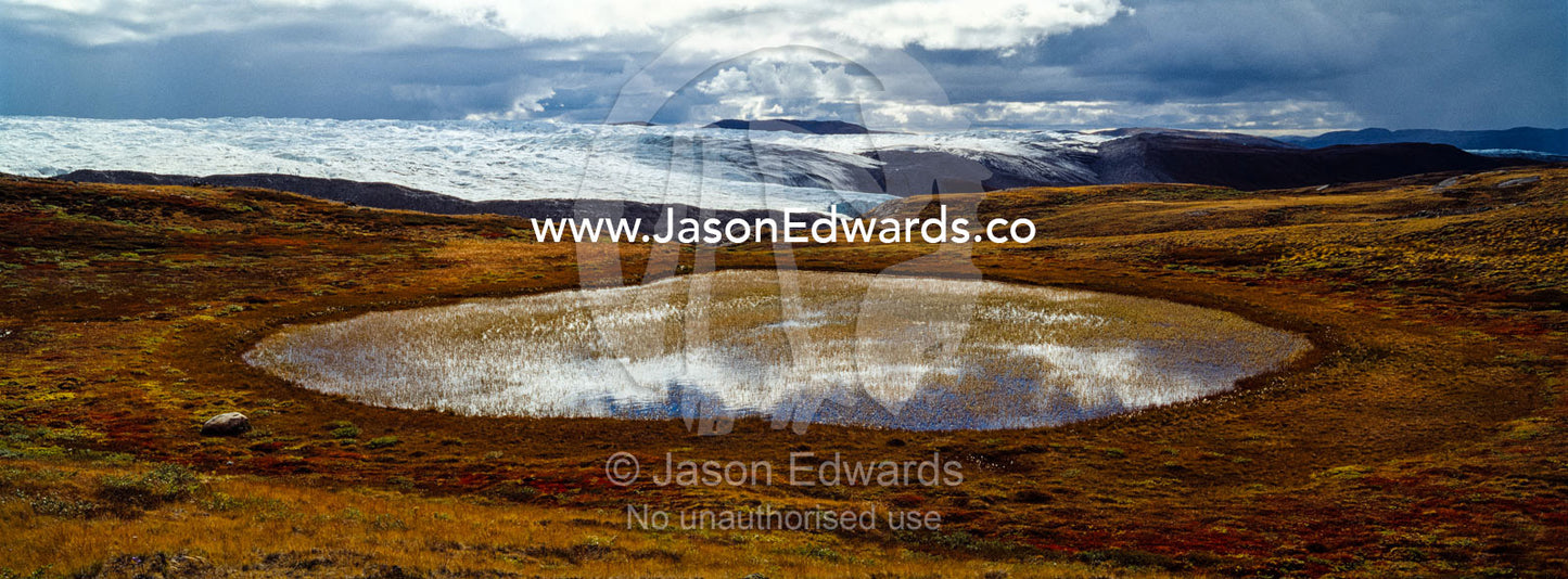 Blue sky and clouds reflected in an alpine pool near the Greenland Ice Sheet. Isunnguata Sermia Glacier, Kangerlussuaq, Qeqqata Municipality, Greenland.
