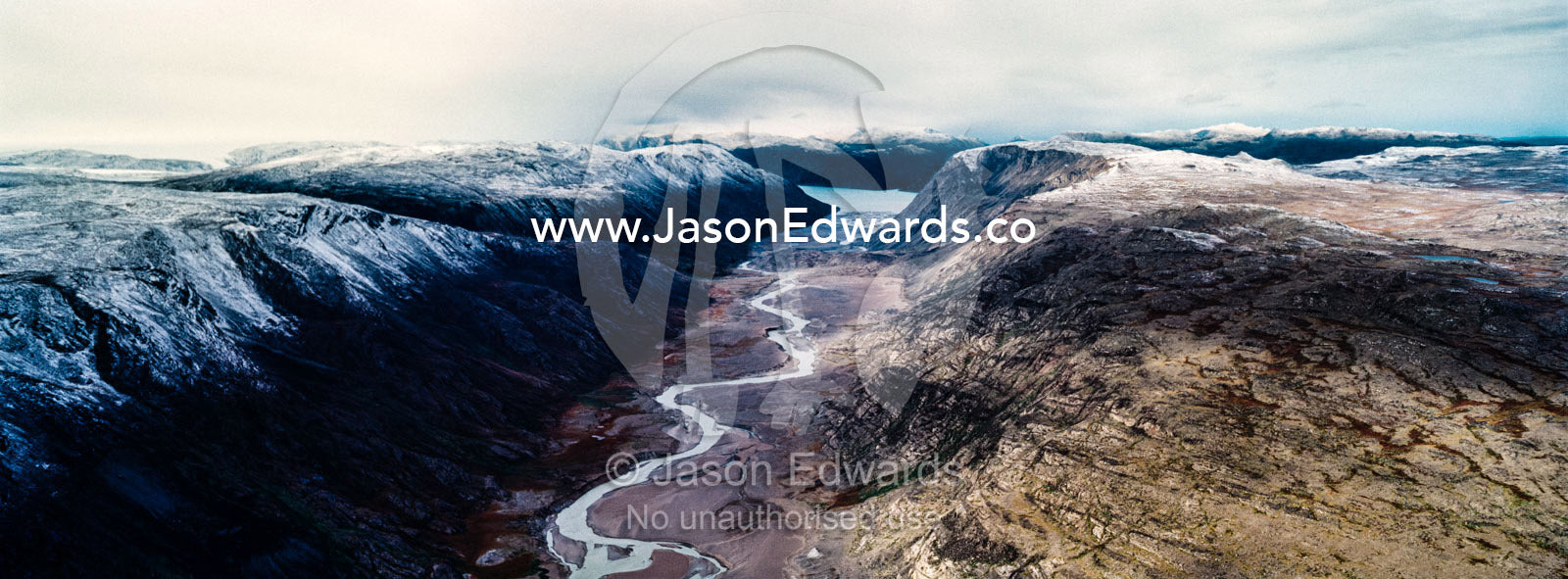 A winding river snakes its way through a highland tundra valley to a fjord. Tarajornitsut Highlands, Qeqqata Municipality, Kangerlussuaq, Greenland.