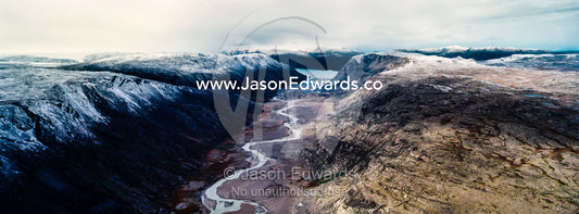 A winding river snakes its way through a highland tundra valley to a fjord. Tarajornitsut Highlands, Qeqqata Municipality, Kangerlussuaq, Greenland.