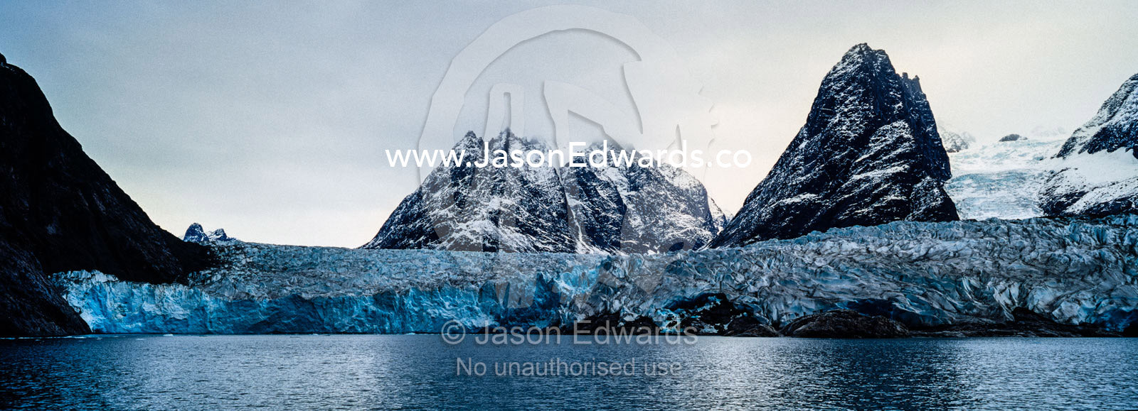 The sheer fracture zone of a glacier sandwiched between alpine peaks in a fjord. Fjord of Eternity, Maniitsoq, Sukkertoppen, Qeqqata Municipality, Greenland.