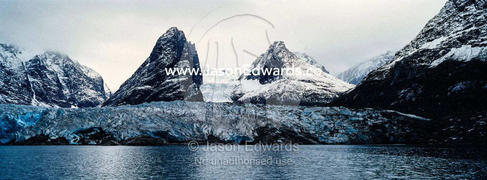 The sheer fracture zone of a glacier sandwiched between alpine peaks in a fjord. Fjord of Eternity, Maniitsoq, Sukkertoppen, Qeqqata Municipality, Greenland.