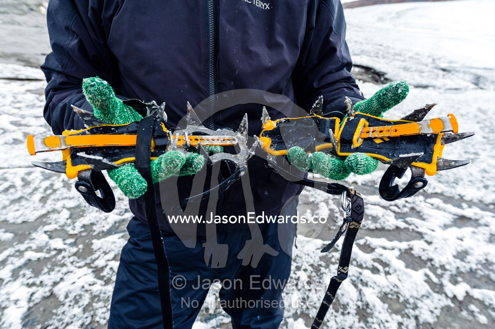 A guide displays the spikes on a pair of crampons for hiking on ice. Isunngua Highland, Greenland Ice Sheet, Kangerlussuaq, Qeqqata Municipality, Greenland.