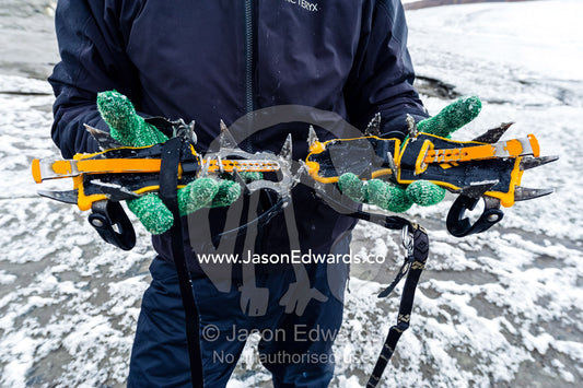 A guide displays the spikes on a pair of crampons for hiking on ice. Isunngua Highland, Greenland Ice Sheet, Kangerlussuaq, Qeqqata Municipality, Greenland.