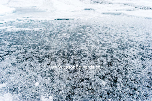 The frozen surface of a melt pond on the surface of the Greenland Ice Shelf. Greenland Ice Sheet, Qeqqata Municipality, Kangerlussuaq, Greenland.