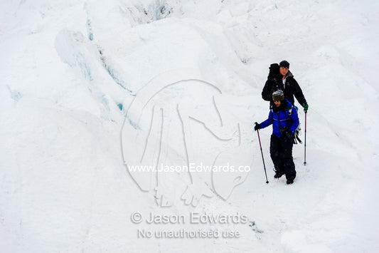 Hikers on the frozen and barren wasteland of folded ice on the surface of the Greenland Ice Sheet. Greenland Ice Sheet, Qeqqata Municipality, Kangerlussuaq, Greenland.