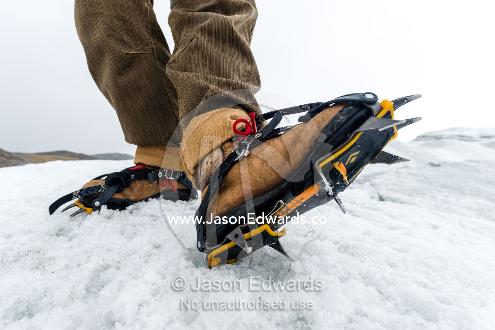 Tourist fitting crampons to their boots to hike on the Greenland Ice Shelf. Greenland Ice Sheet, Qeqqata Municipality, Kangerlussuaq, Greenland.