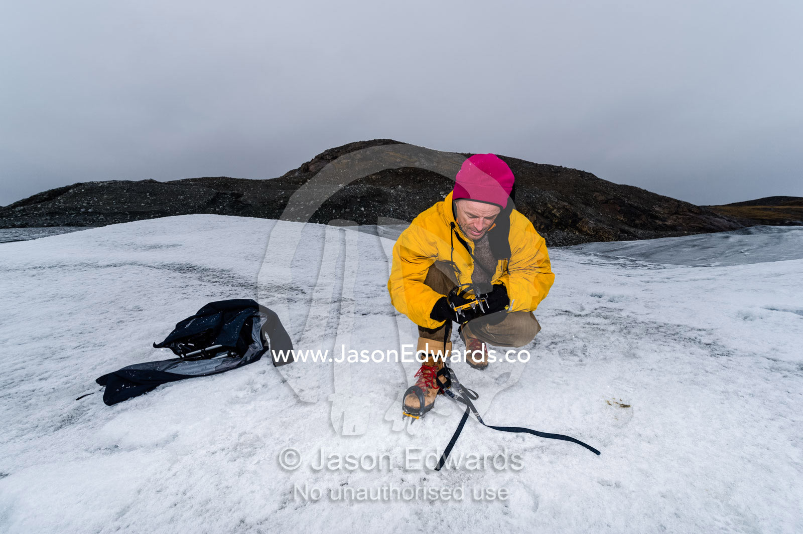 Tourist fitting crampons to their boots to hike on the Greenland Ice Shelf. Isunngua Highland, Greenland Ice Sheet, Kangerlussuaq, Qeqqata Municipality, Greenland.