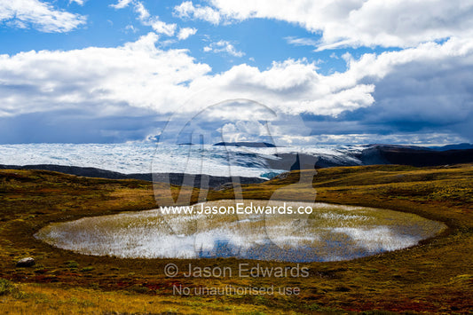Blue sky and clouds reflected in an alpine pool near the Greenland Ice Sheet. Isunnguata Sermia, Kangerlussuaq, Qeqqata Municipality, Greenland.