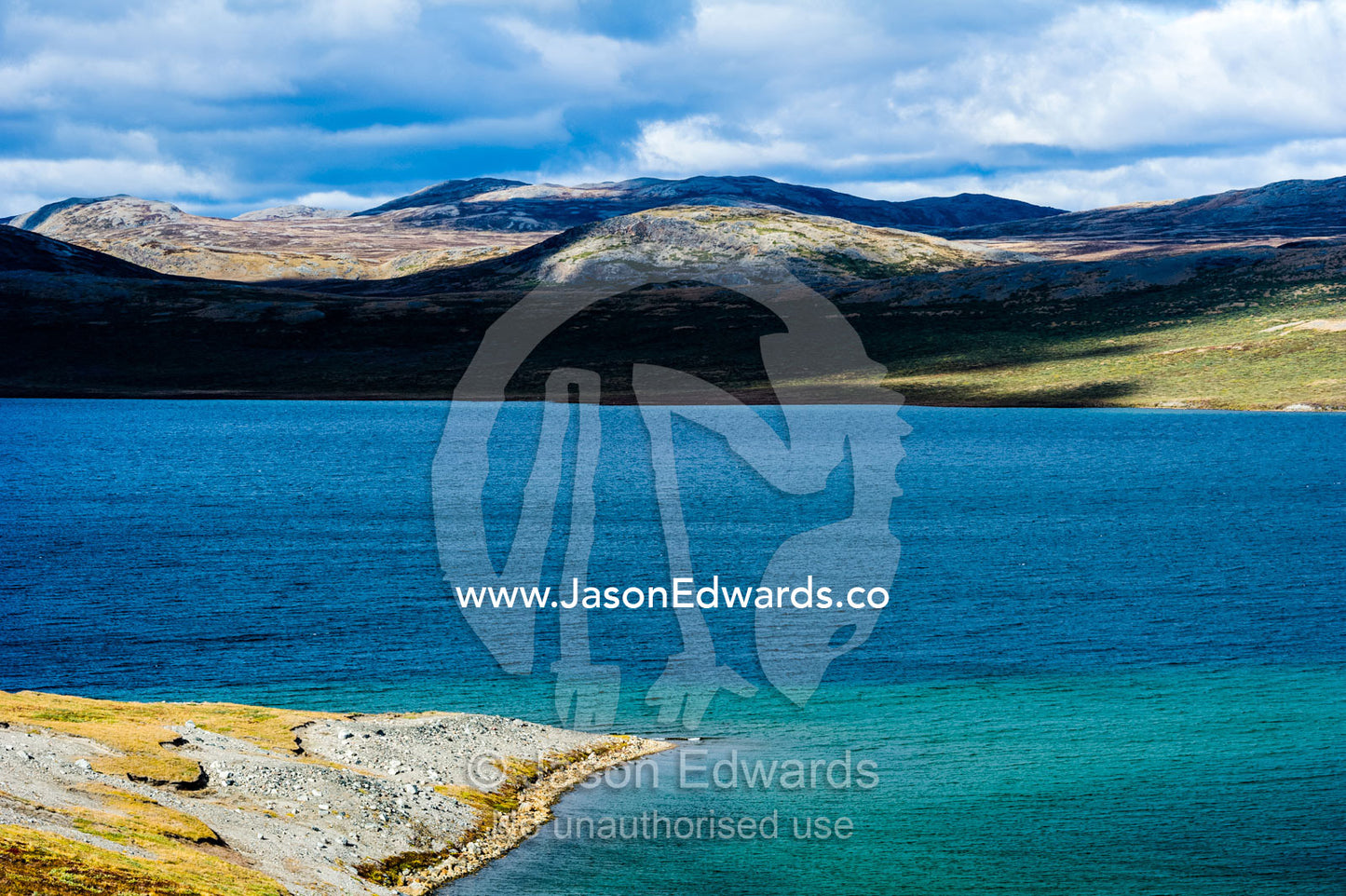 A clear blue alpine lake surrounded by mountains. Isunnguata Sermia, Kangerlussuaq, Qeqqata Municipality, Greenland.